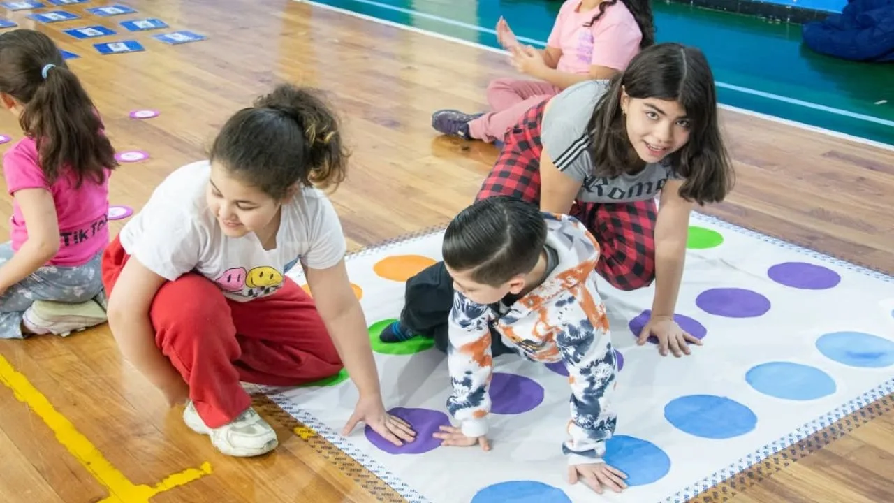 Niños y adultos jugando en un gimnasio municipal de Río Grande con colchonetas y pelotas