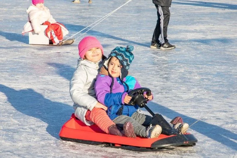 Niños y familias patinando y jugando con trineos en la pista nevada del Cono de Sombra, Ushuaia