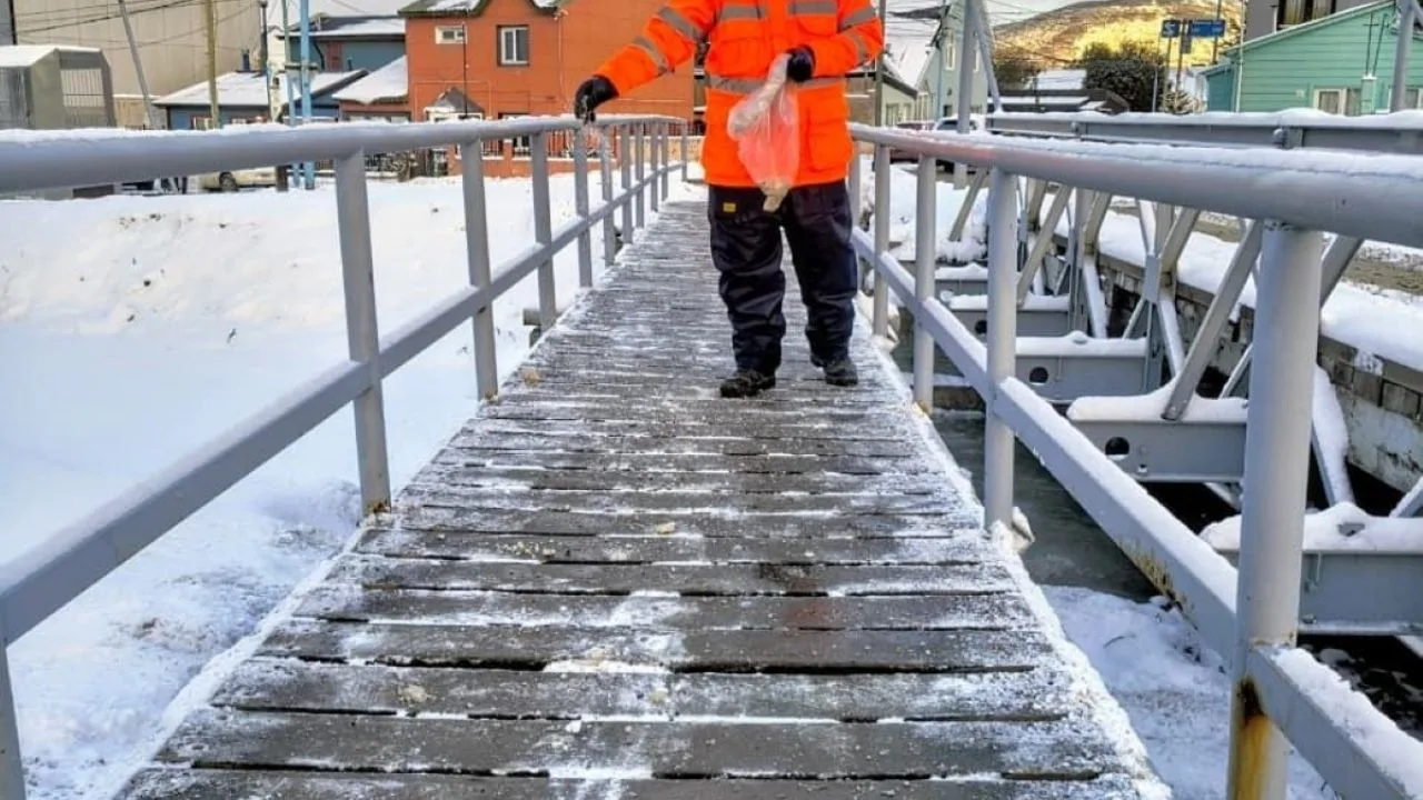 Camión quitanieves trabajando en una calle nevada de Ushuaia con operarios municipales