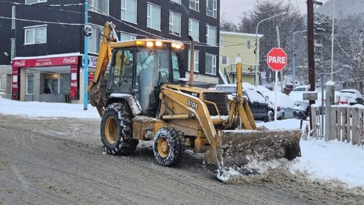 Camiones y máquinas quitanieves trabajando en avenidas nevadas de Ushuaia al amanecer