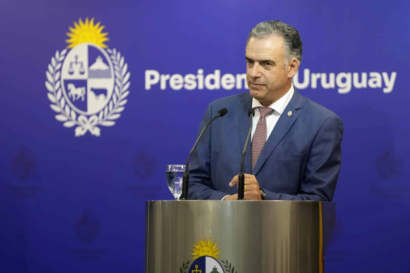 Yamandú Orsi en conferencia de prensa con fondo de banderas de Uruguay y Estados Unidos