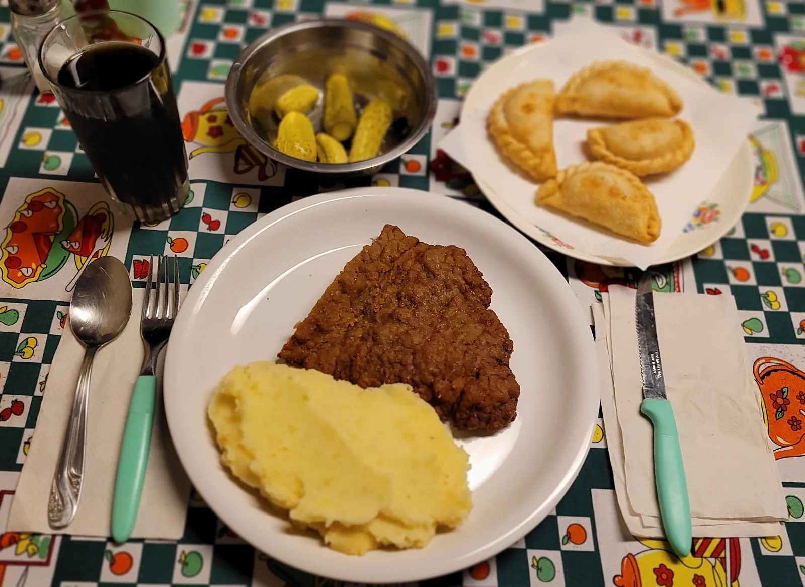 Milanesa con puré de papas, empanadas de jamón y queso y pickles de pepinos.