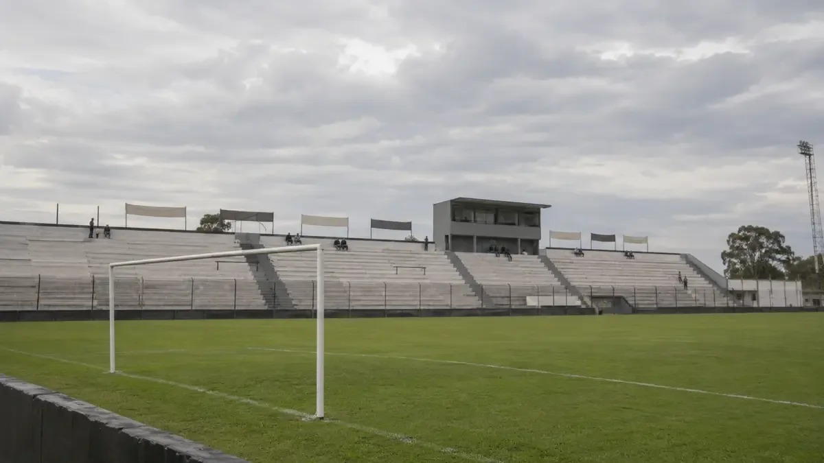 Tribuna y campo de un estadio de fútbol de ascenso en el conurbano.